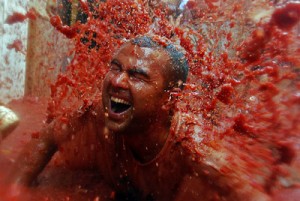 Un participante recibe una explosión de zumo de tomate sobre su cuerpo durante la fiesta de la Tomatina de Buñol. / HEINO KALIS (REUTERS)